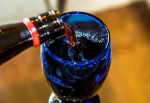 red wine pouring into blue crystal glass