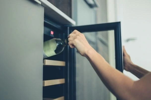 woman getting a bottle of wine from a cooler